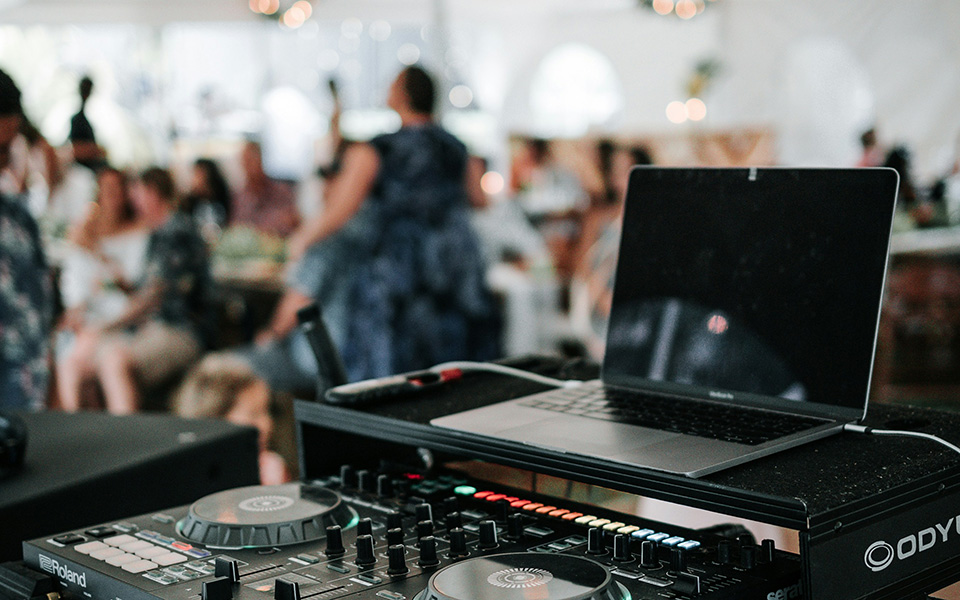 una mesa de mezclas de DJ, una boda al fondo